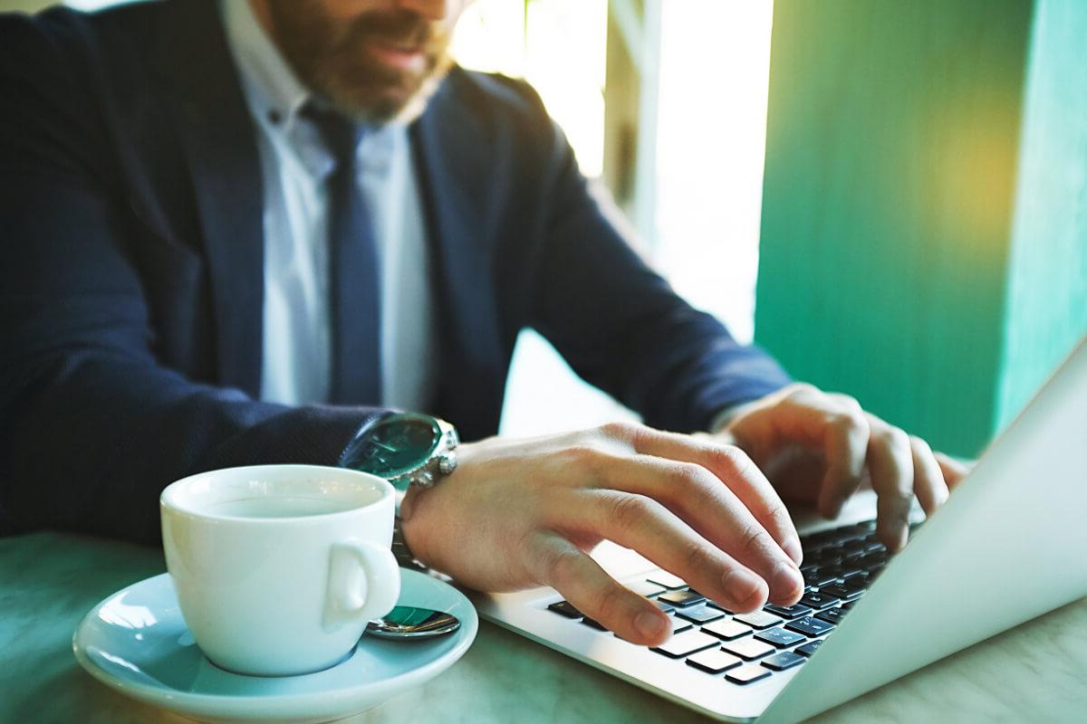 Businessman Working Remotely on Laptop in Coffee Shop VoIP Technology Concept